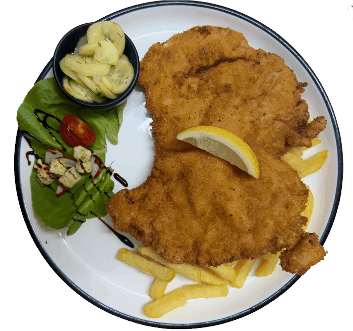 Ein Teller mit einem Schnitzel, Zitronenscheibe, Gurkensalat und Pommes